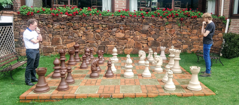 Two men playing a giant chess board on the ground